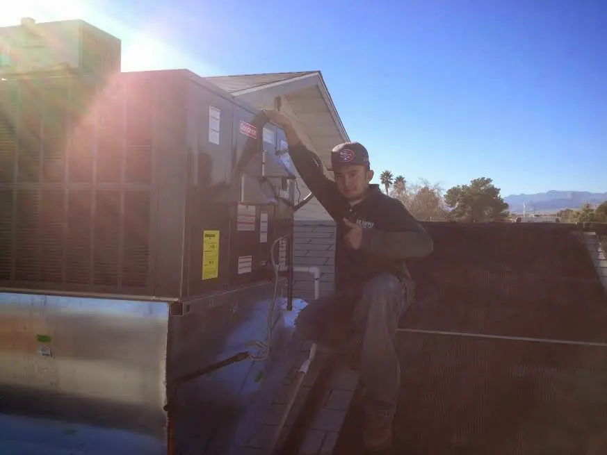 HVAC technician performing Air Duct Cleaning on a rooftop unit in Wells
